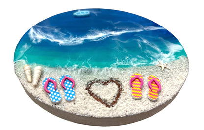 Round beach view wall hanging with resin ocean waves, sandy shore, colorful flip-flops, seashells, starfish, and heart shape design.