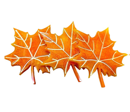 Set of three handmade maple leaf resin coasters in bright autumn orange color with detailed veins, perfect for fall decor and nature lovers.