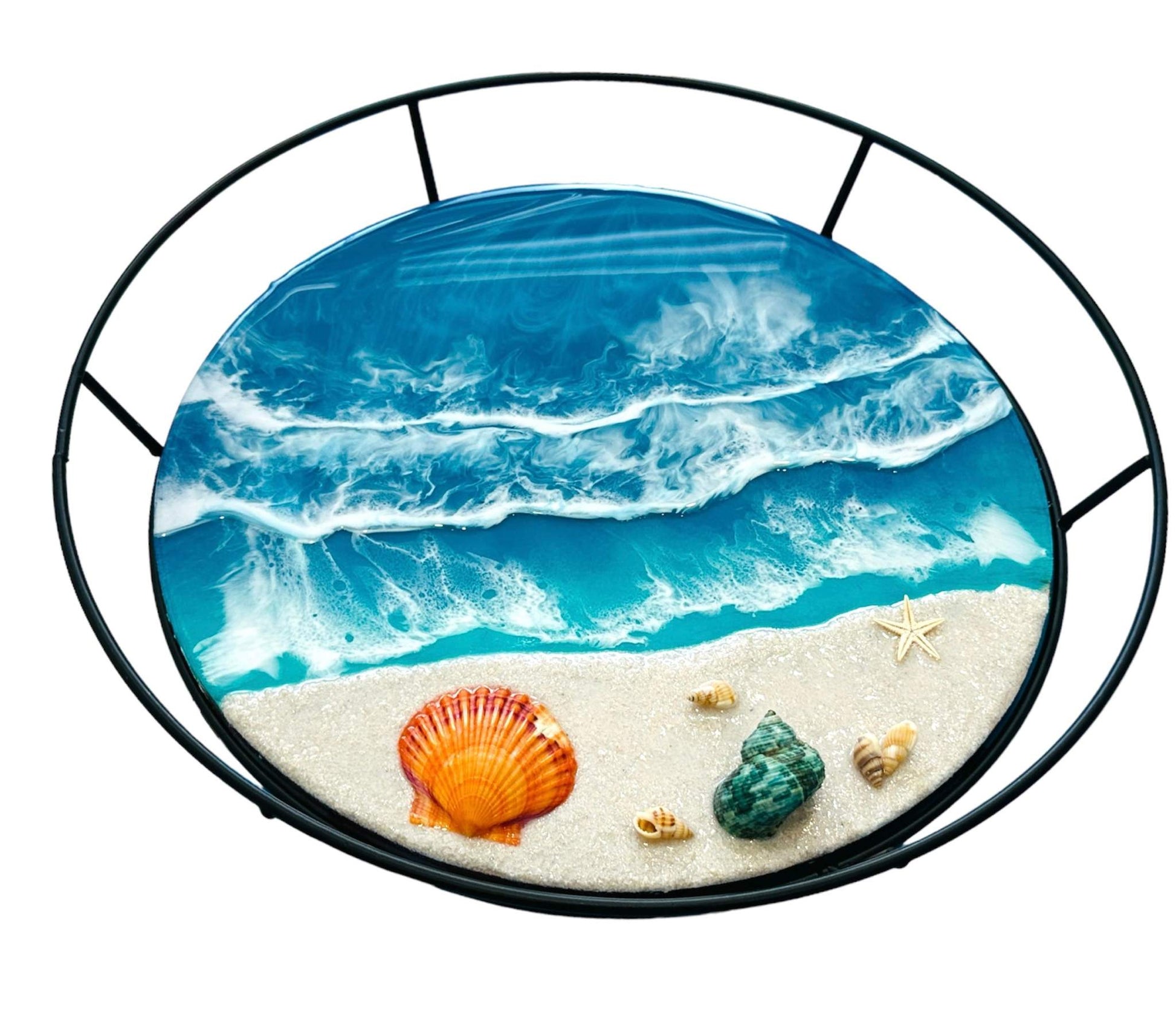 Round metal frame tray with ocean wave design, seashells, and starfish on sandy shore surface