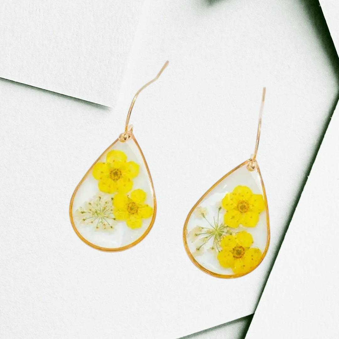 Handcrafted drop-shaped earrings with real dried yellow flowers encased in clear resin and 14K gold plated hooks