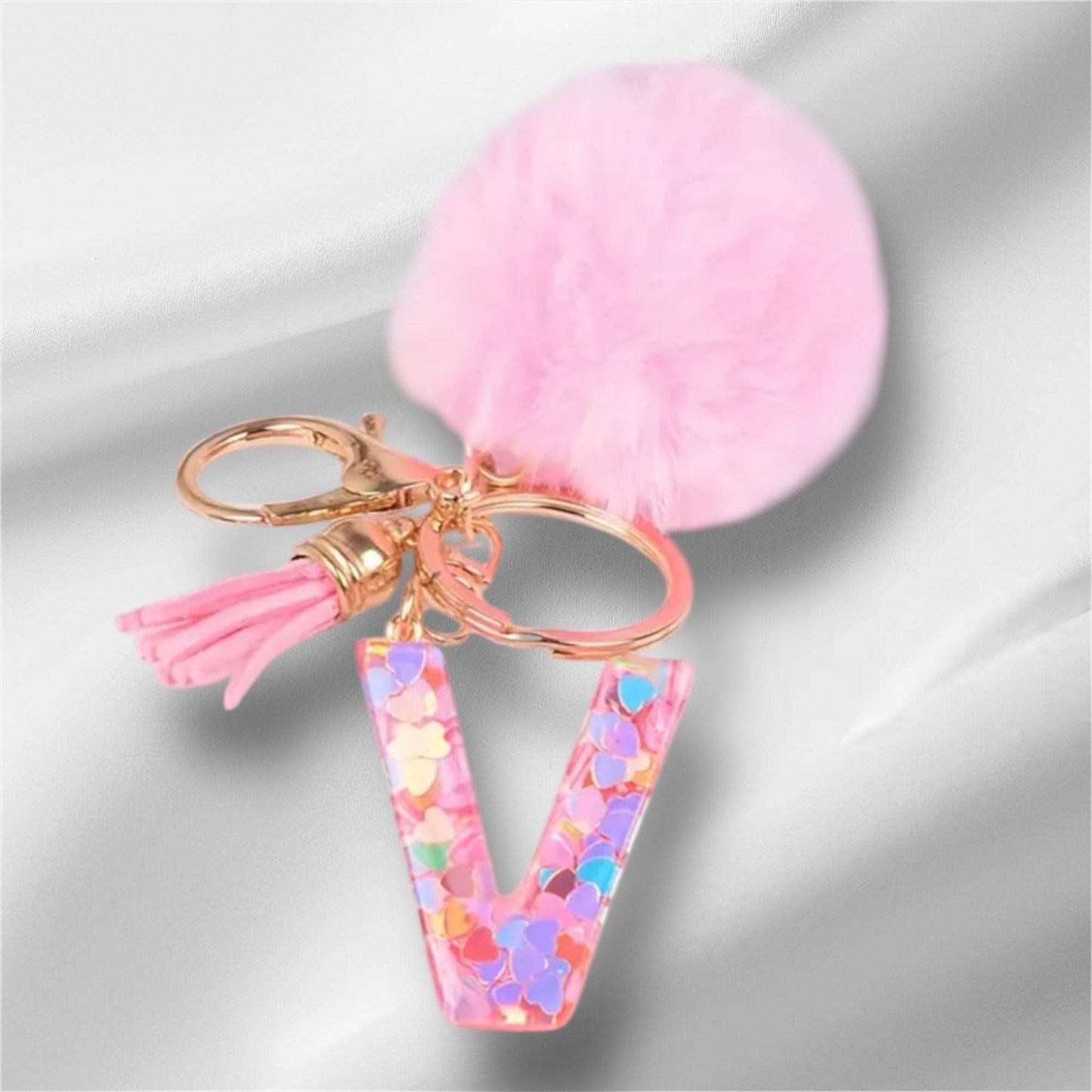 Pink alphabet keychain with letter V, confetti design, and fluffy pom-pom accessory