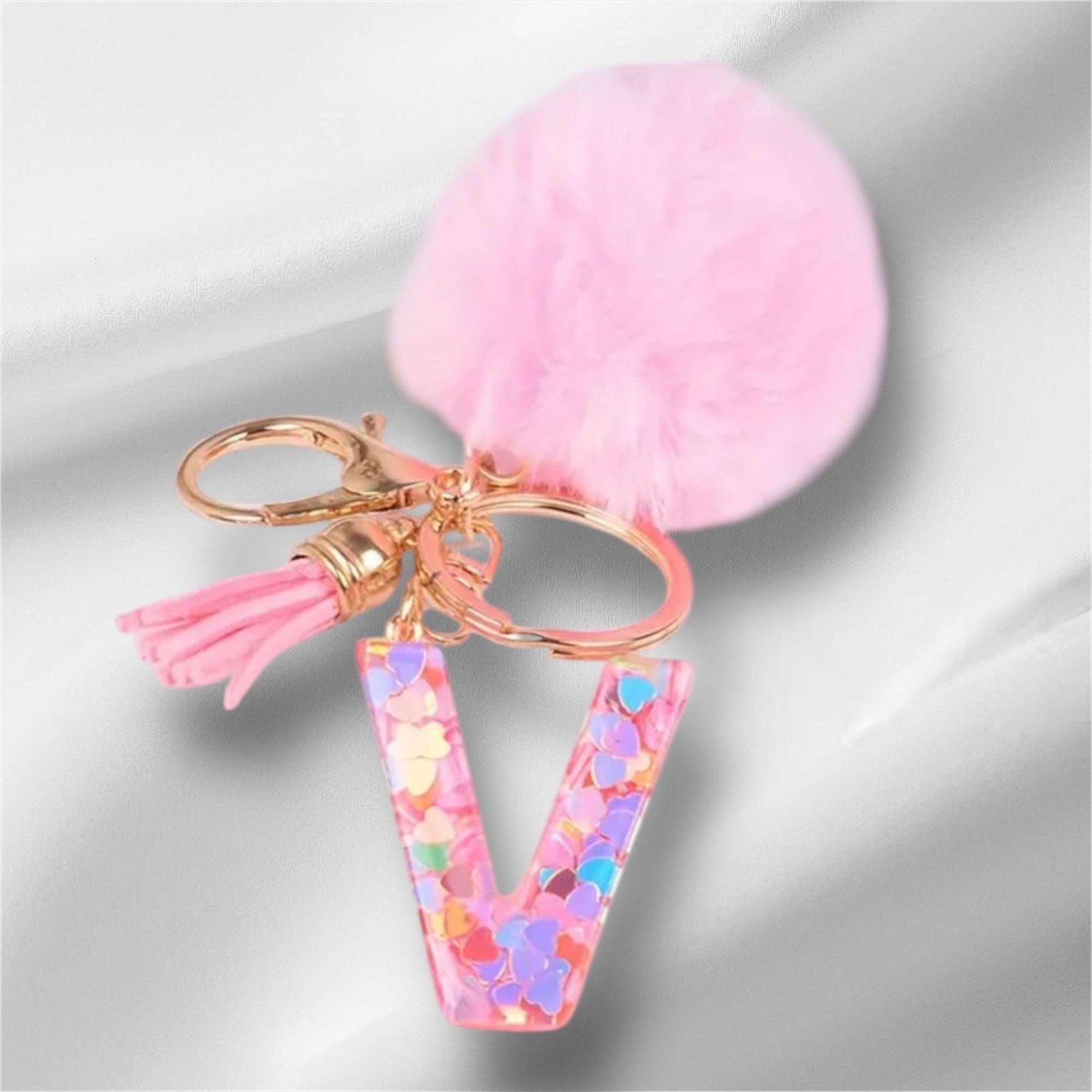 Pink alphabet keychain with letter V, confetti design, and fluffy pom-pom accessory