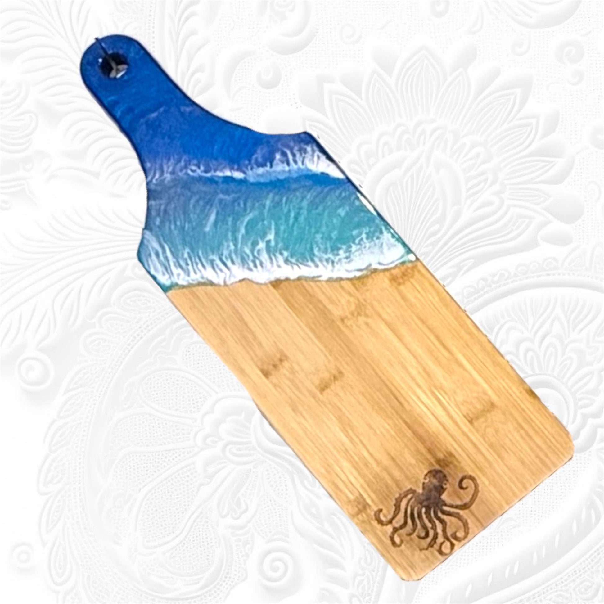 Ocean wave resin cheese board with handcrafted ocean-inspired resin art on bamboo wood featuring blue and white wave design and octopus engraving.