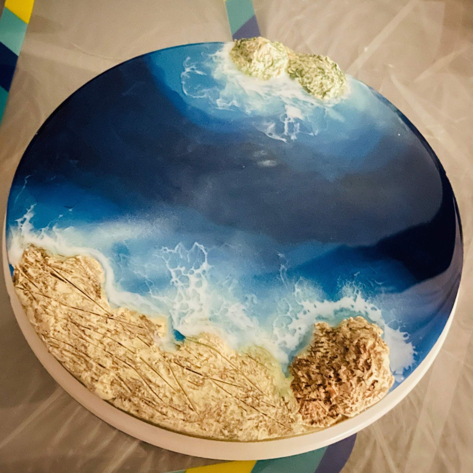 Round 8-inch handcrafted ocean art with sand and rock effects in vibrant blue resin decor