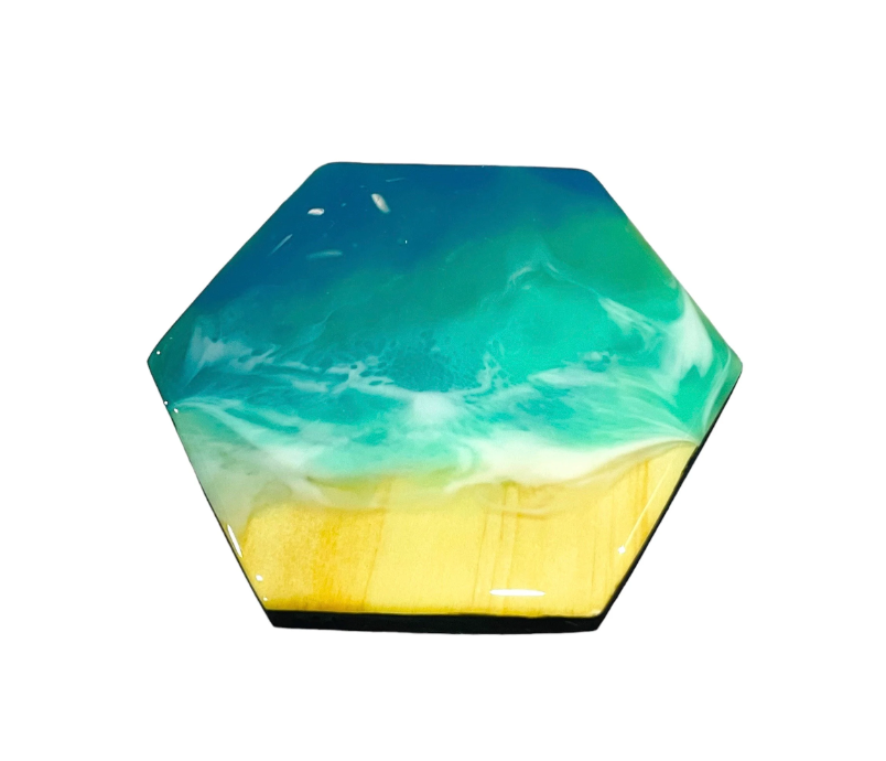 Hexagonal ocean wave resin coaster with blue and white waves over sandy beach design, handmade coastal home decor accessory